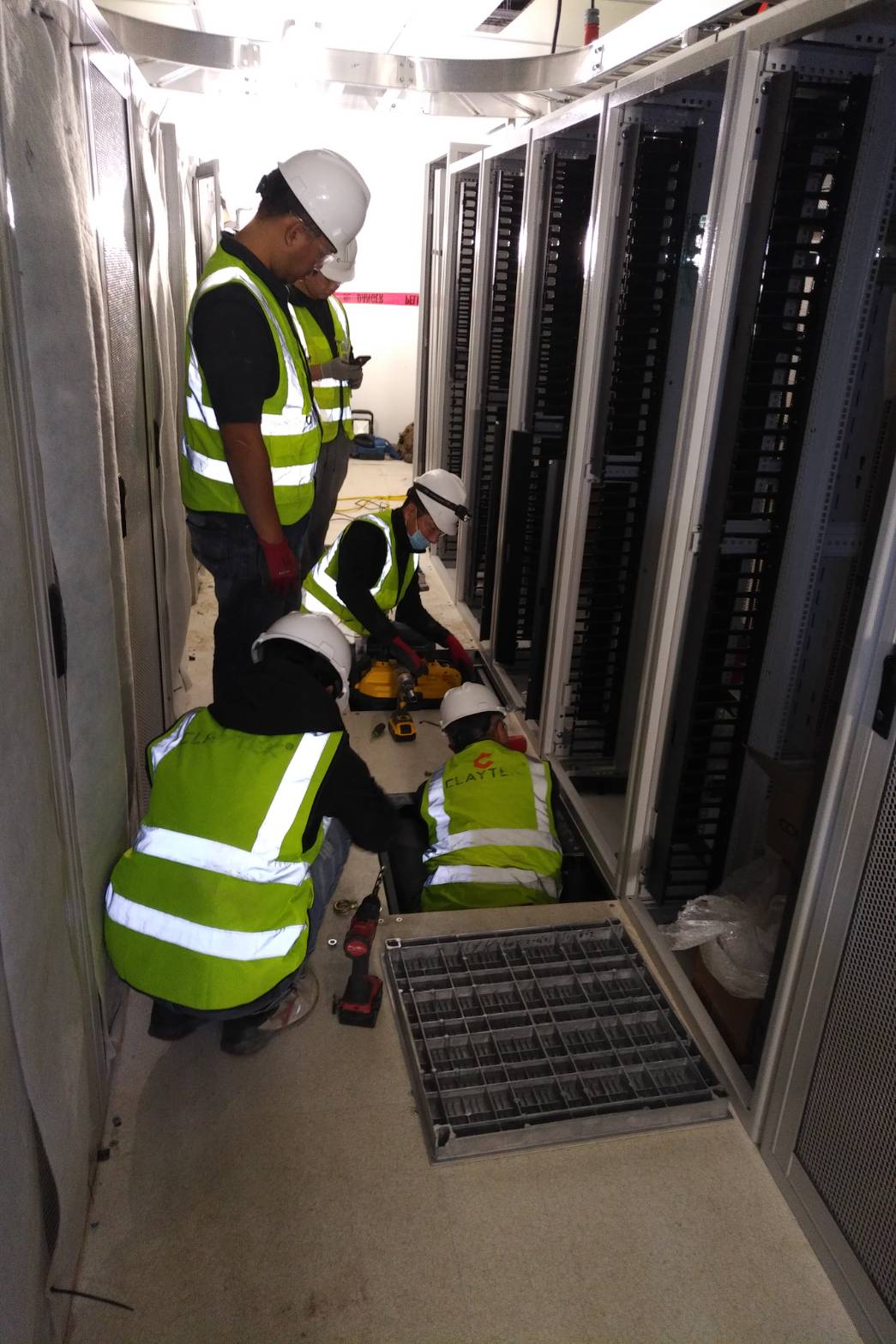 Claytek crew working in a cabinet aisle with the raised floor tile pulled