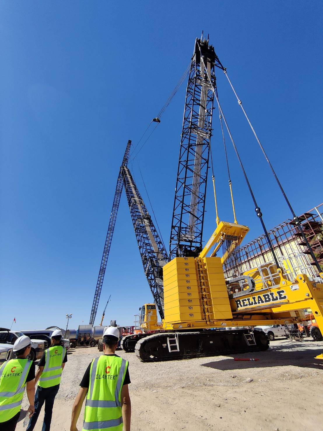 Claytek field team on a construction pad beside a crawler crane