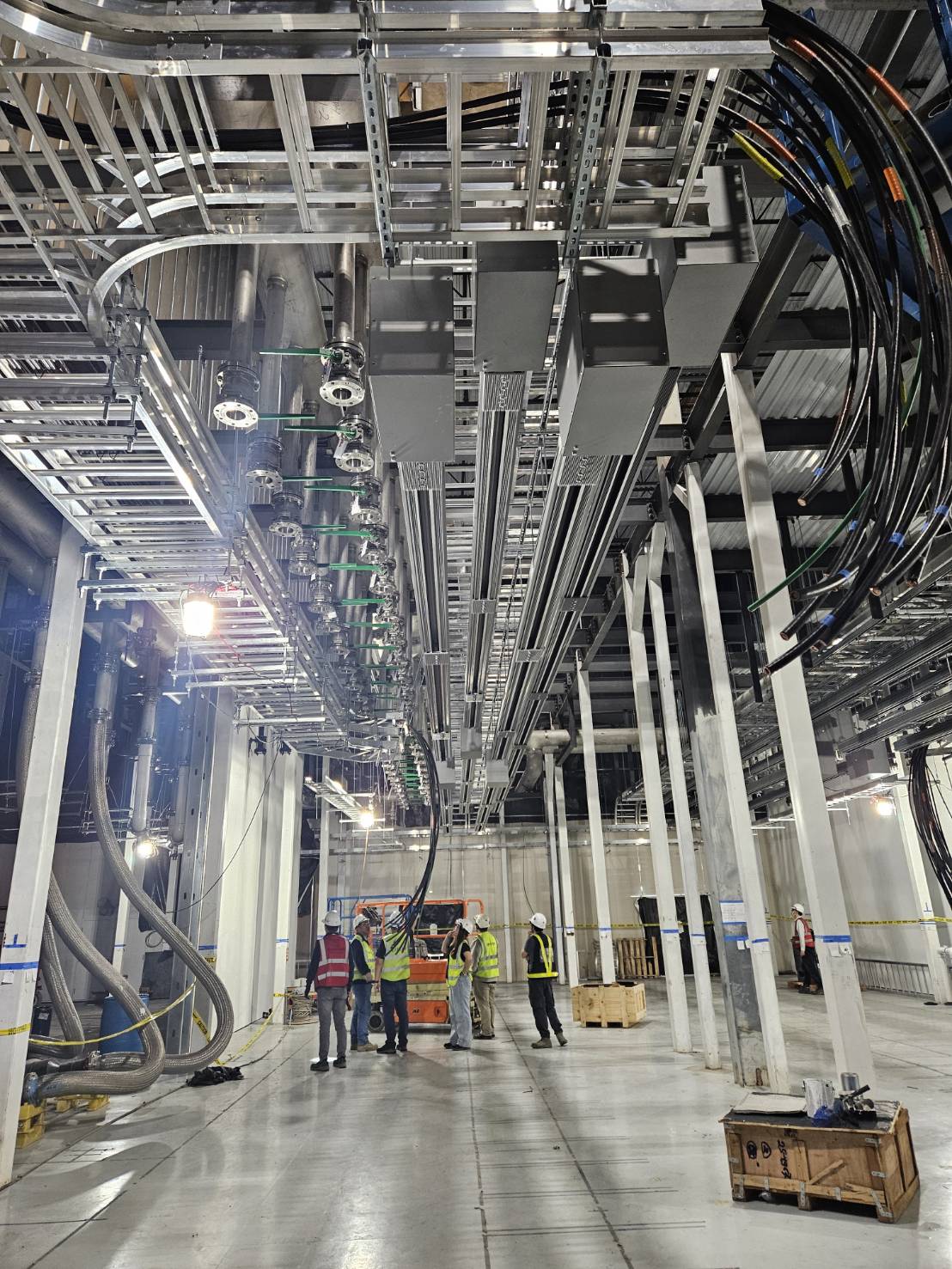 Data hall with overhead busway, piping, and tray before equipment land