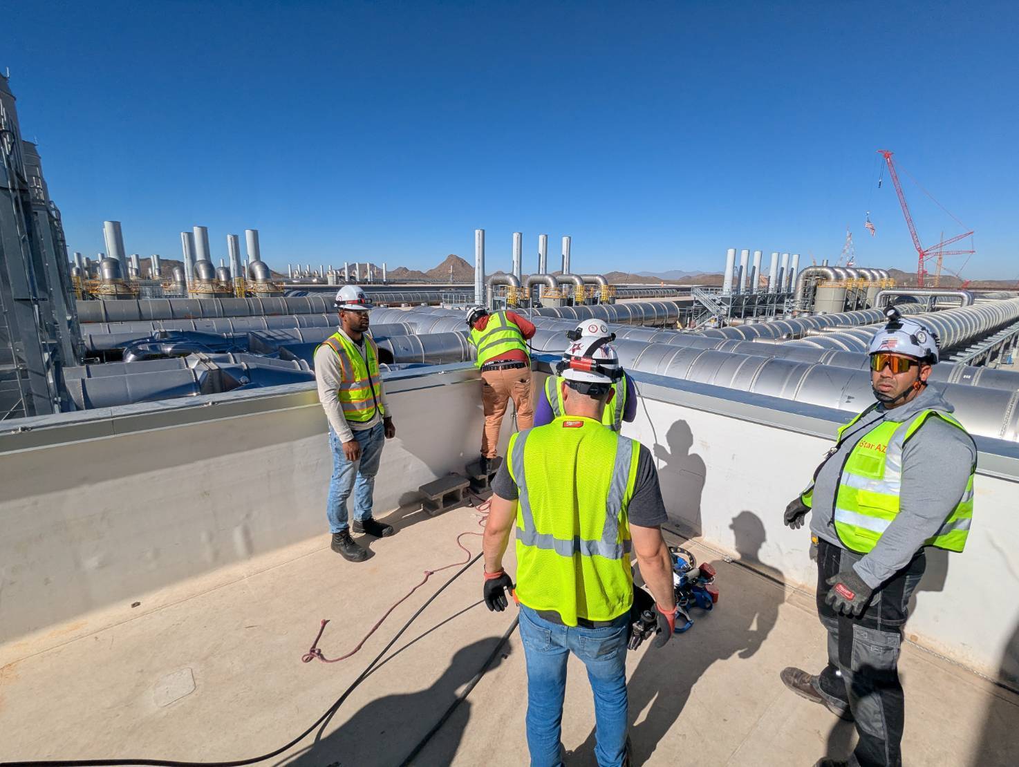 Field team coordinating on a rooftop mechanical deck above a data hall